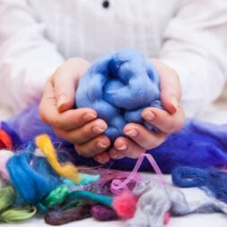 Eine Person hält bunte gefilzte Wolle in den Händen